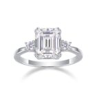 A breathtaking 5-carat emerald-cut moissanite framed by twin round stones, set on a sleek polished band for a crisp, high-clarity sparkle. Bold, refined, and timeless — a statement piece made to captivate