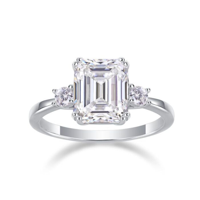 A breathtaking 5-carat emerald-cut moissanite framed by twin round stones, set on a sleek polished band for a crisp, high-clarity sparkle. Bold, refined, and timeless — a statement piece made to captivate A breathtaking 5-carat emerald-cut moissanite framed by twin round stones, set on a sleek polished band for a crisp, high-clarity sparkle. Bold, refined, and timeless — a statement piece made to captivate
