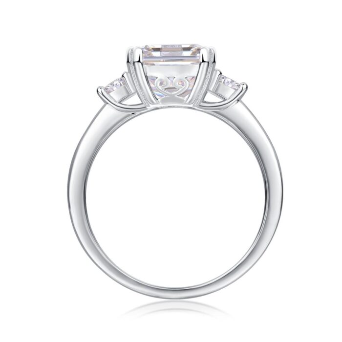 A breathtaking 5-carat emerald-cut moissanite framed by twin round stones, set on a sleek polished band for a crisp, high-clarity sparkle. Bold, refined, and timeless — a statement piece made to captivate A breathtaking 5-carat emerald-cut moissanite framed by twin round stones, set on a sleek polished band for a crisp, high-clarity sparkle. Bold, refined, and timeless — a statement piece made to captivate